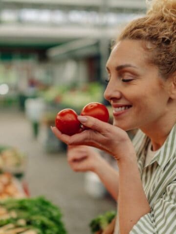 happy woman smelling tomatoes