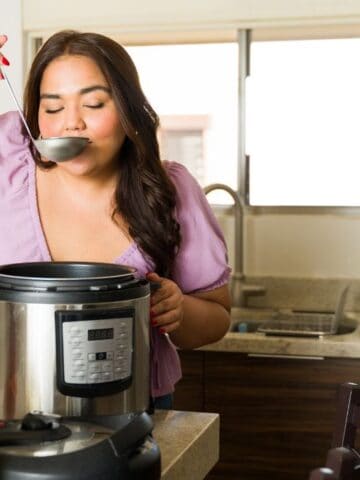 woman drinking from ladle with slow cooker