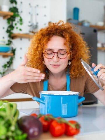 woman smelling soup on stove