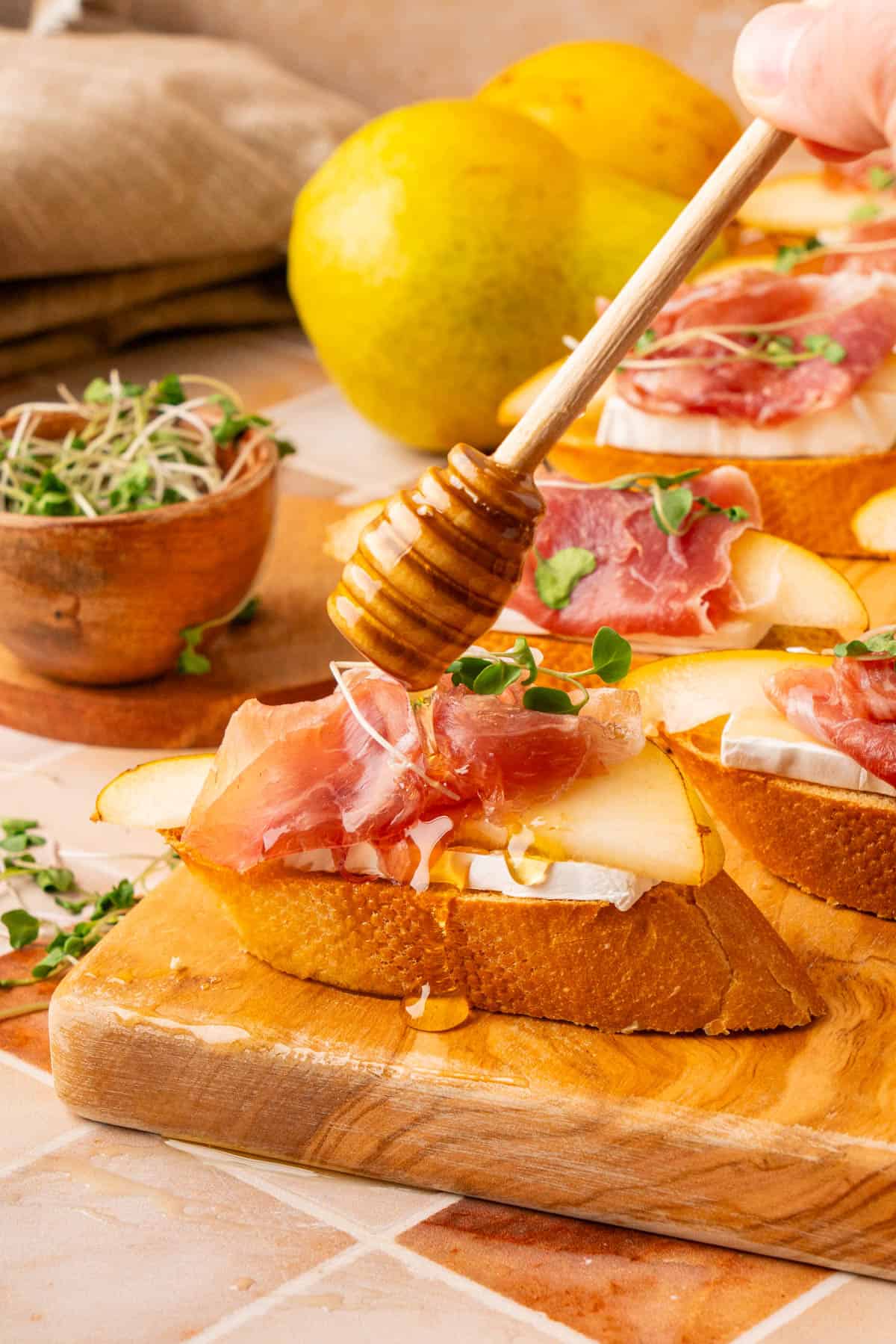 A shot of a drizzle of honey dripping onto the fully prepared crostini