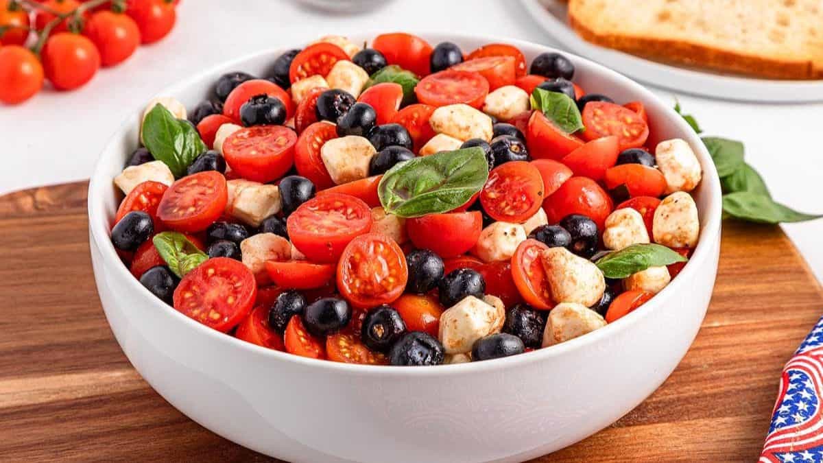 A white bowl filled to brim with Blueberry Tomato Caprese.