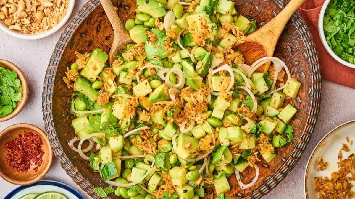 A top shot of Crispy rice salad served on a brown mixing bowl with two wooden spoons.