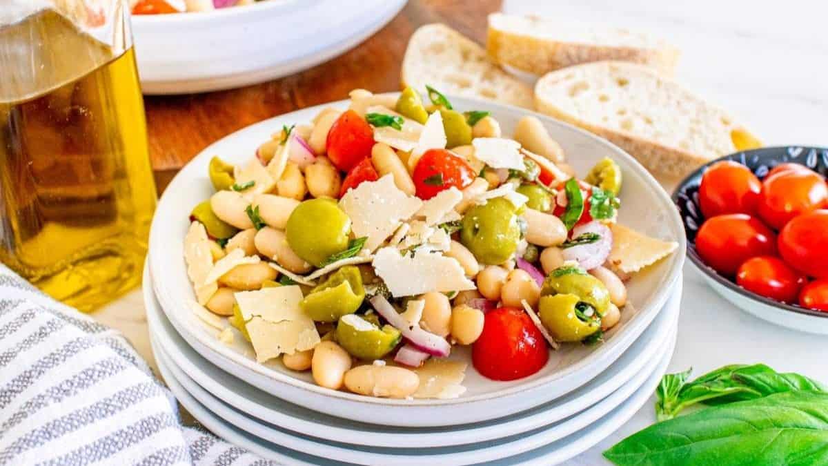 A stack of white plates, and the top plate filled with a serving of Italian White Bean Salad.