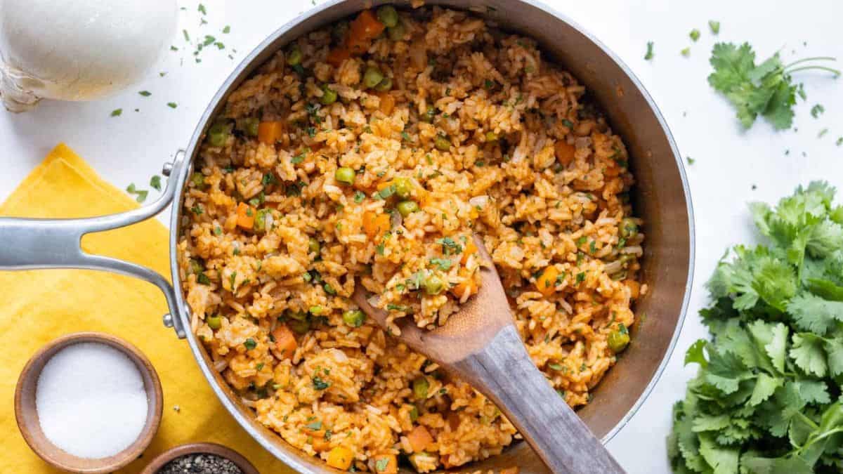 A pot filled with Mexican Rice with wooden spoon.
