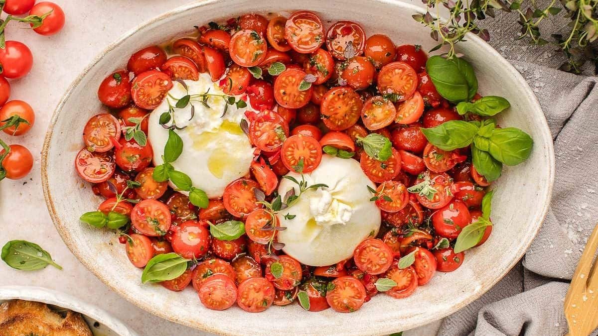 A top shot of a serving platter bowl filled with Tomato Burrata Salad. 