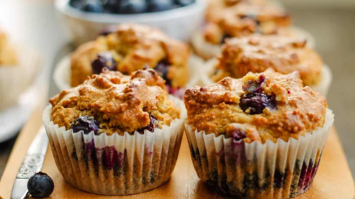 A close-up shot of a couple of blueberry muffins set on a wooden tray.