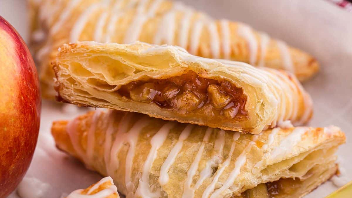 A close-up shot of Apple Turnovers sliced in half and filling can be seen in the middle part of the puff pastry. 