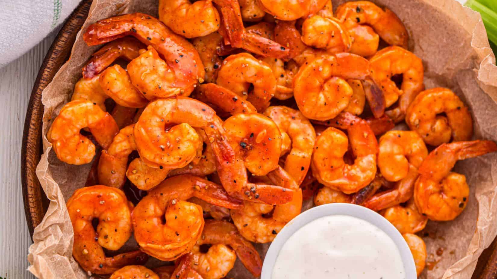 A plate filled with Buffalo shrimp and a side dip