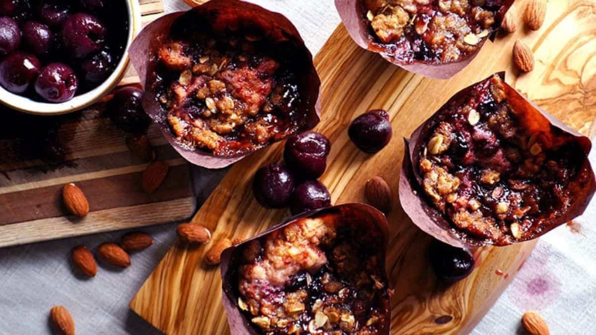 Top shot of 4 pieces of Cherry Almond Muffins with Streusel lay flat on a surface.