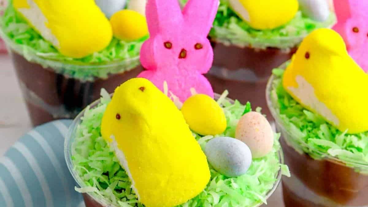 A couple of easter dirt cups desserts all topped with a couple of egg chocolate, and bunny and bird mallows.