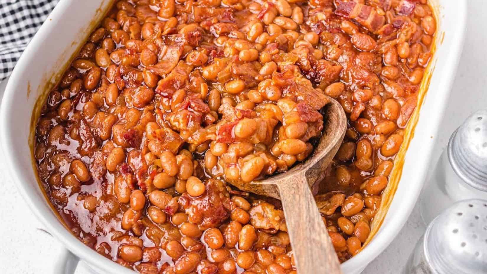 Baked Beans with Bacon on a baking dish with a wooden spoon. 