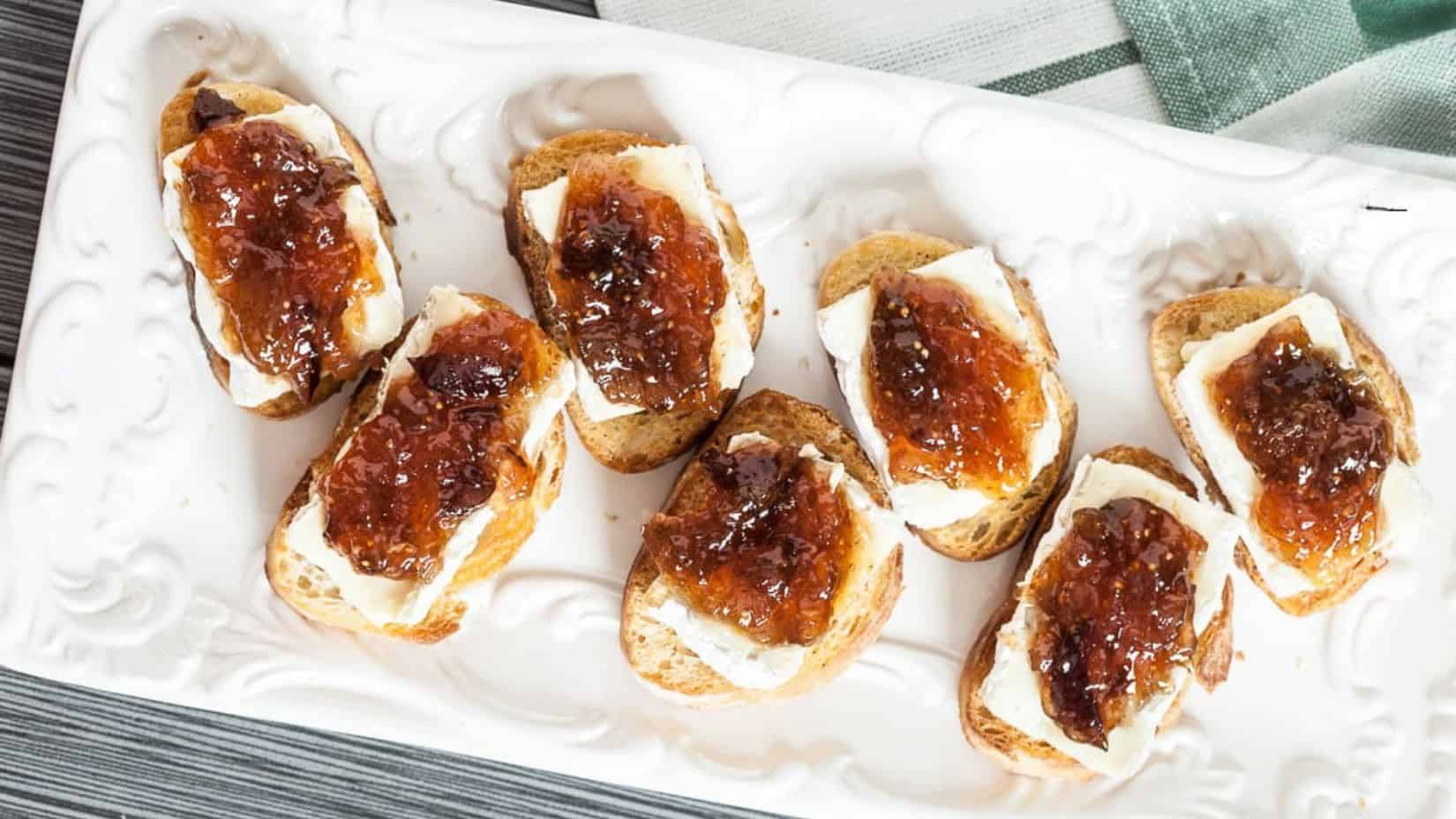 A few pieces of Brie and Fig Crostini plated in a rectangular white serving plate. 