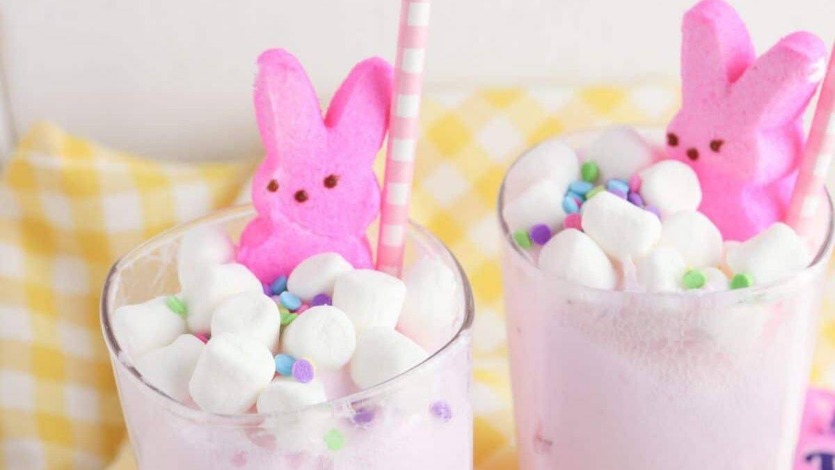 Two glasses of easter punch, topped with pink peeps mallows and some white mallows, both adorned with pink and white straws. 