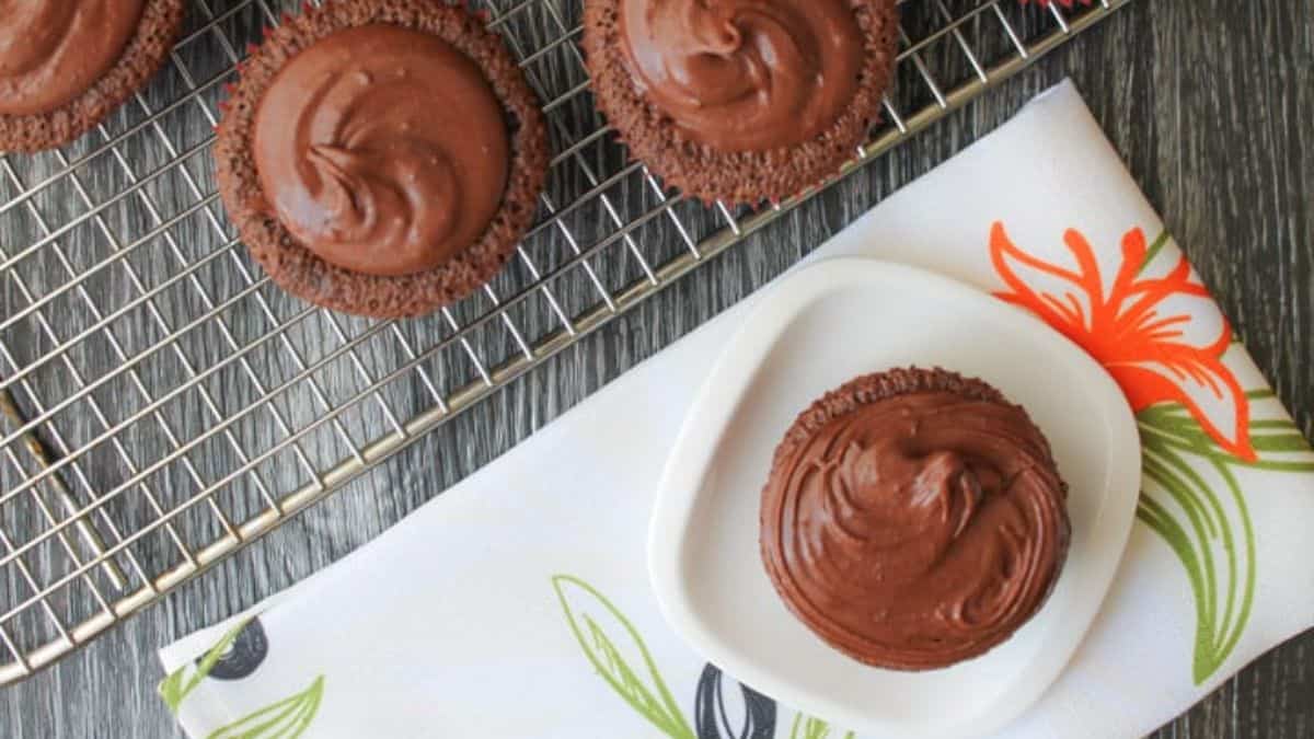 Top shot of chocolate muffins lay flat on a plate and some on a wire rack.