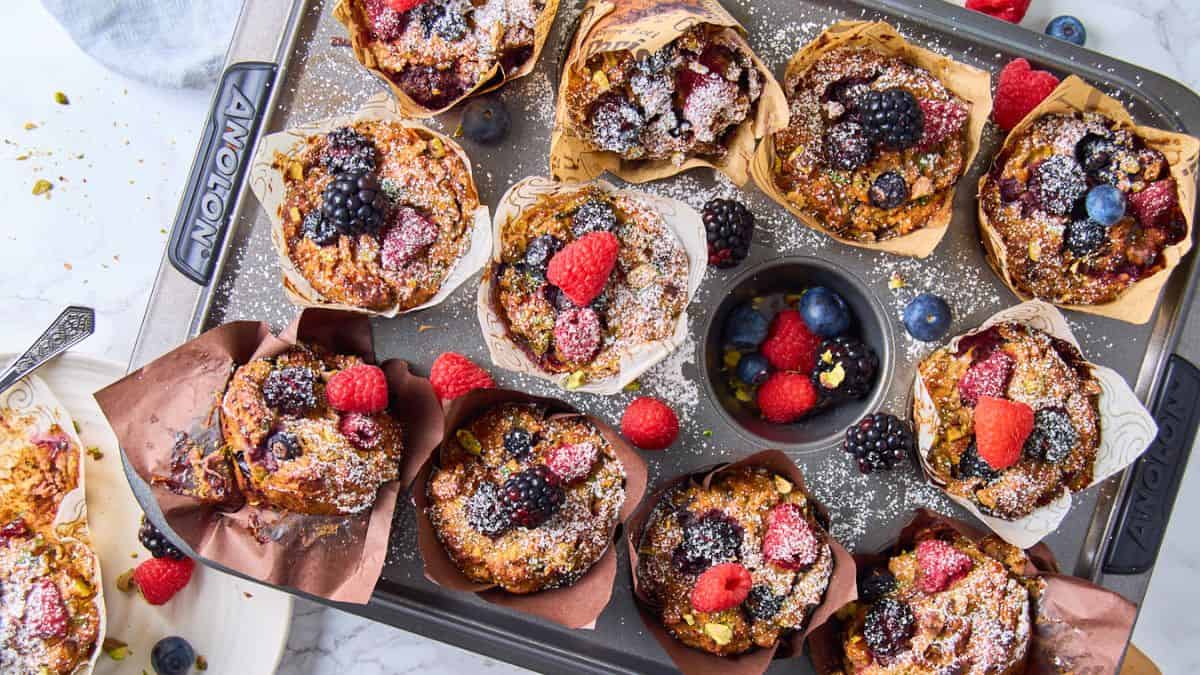 Top shot of A muffin tray filled with Muffins topped with berries.