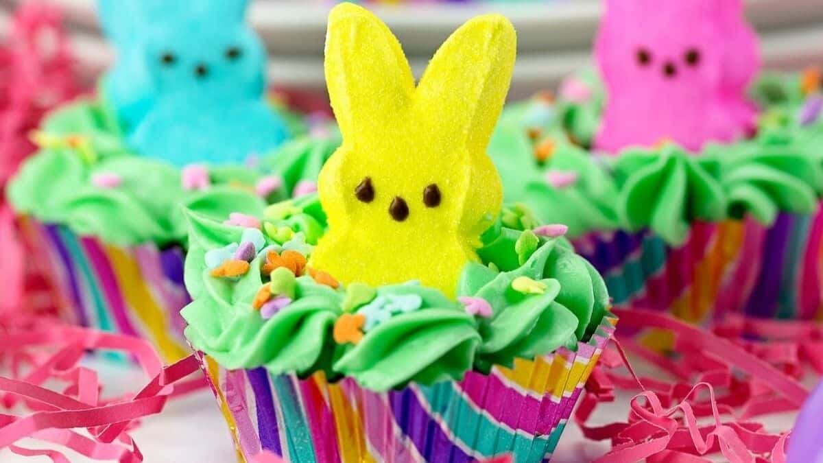 A close-up shot of a bunny cupcakes all topped with peeps bunny mallows. Center with a yellow bunny, and the other two cupcake serving with yellow and blue bunny toppings. 