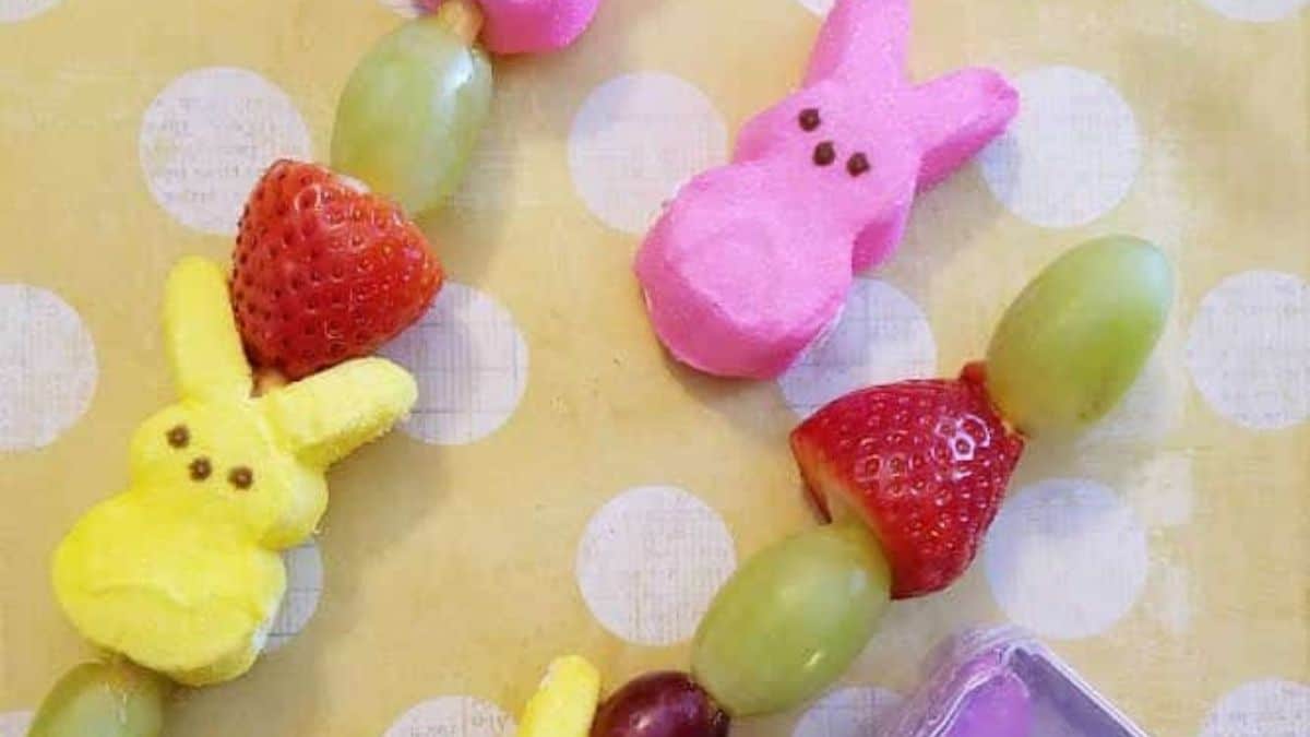 A top shot of two sticks of peeps bunny kabobs with strawberries and grapes. 
