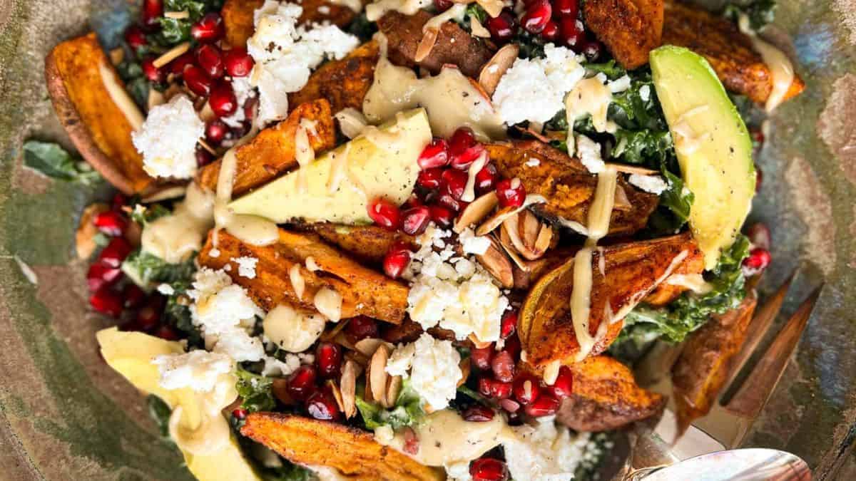 A close-up of Roasted Sweet Potato & Kale Salad with a drizzle of tahini. 