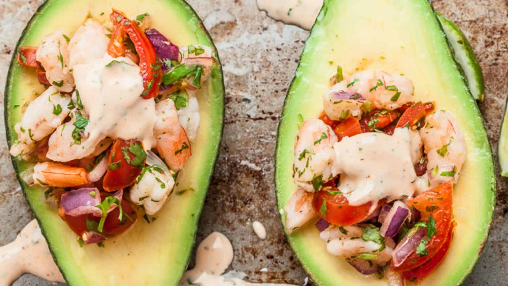 Two half slices of avocado with some shrimp salad nestled in the middle hollow place of the fruit. 