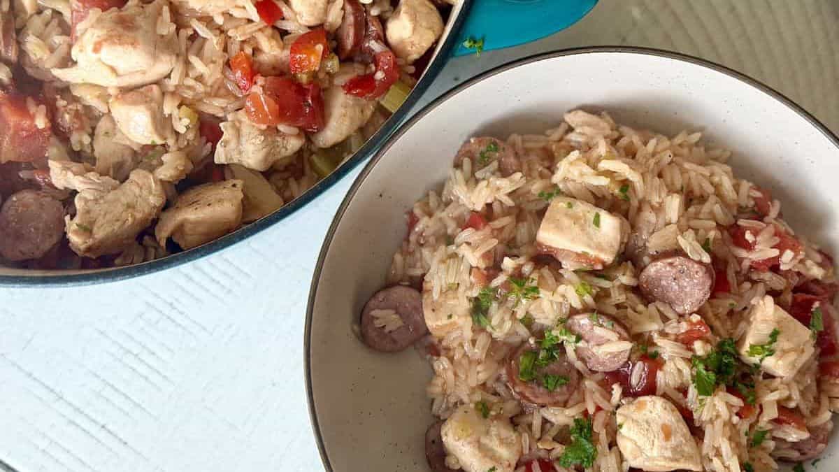 A pot and a bowl filled with Chicken and Sausage Jambalaya.