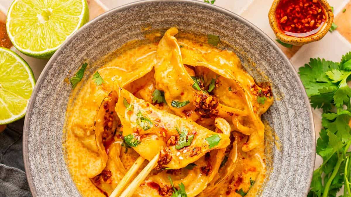 A bowl filled with dumpling bake, and a chopstick holding unto one piece of dumpling.