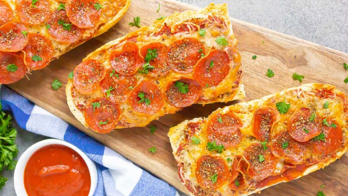 Top shot of three pieces bread pizza, set on a wooden tray with some sauce on the side.