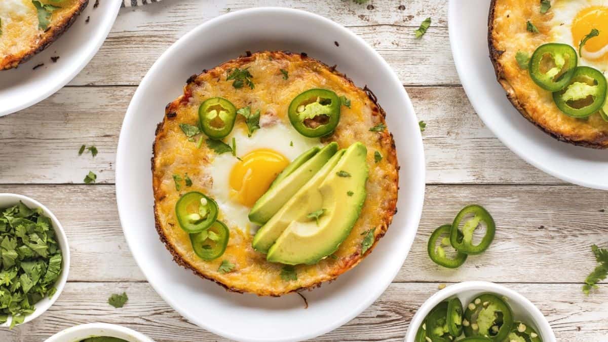 Top shot of three bowls with BBQ Skillet Huevos Rancheros topped with egg, and some slices of avocado. 