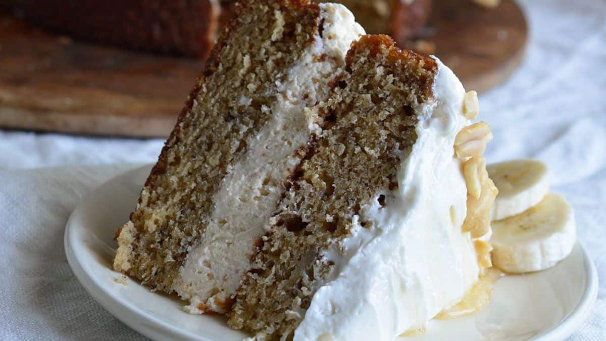 Banana layer cake with peanut butter honey frosting on a plate.