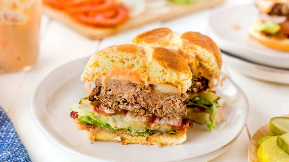 A plate of a burger sliced into two pieces set on a plate. 
