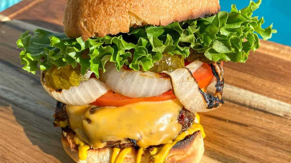 A cheese burger set on a wooden tray.