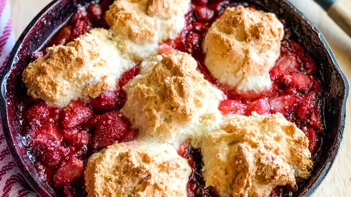 A close-up shot of a Bisquick strawberry Cobbler cooked in a cast iron pan.