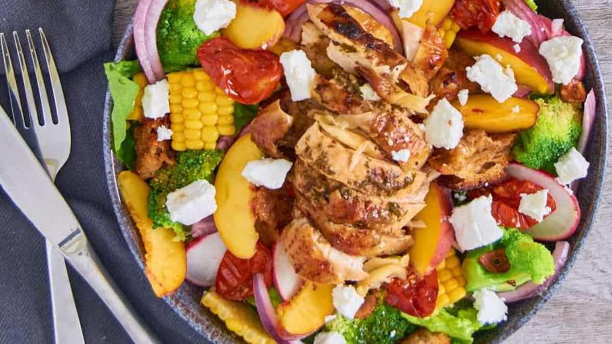 Black garlic roast chicken served over summer greens with vibrant vegetables.