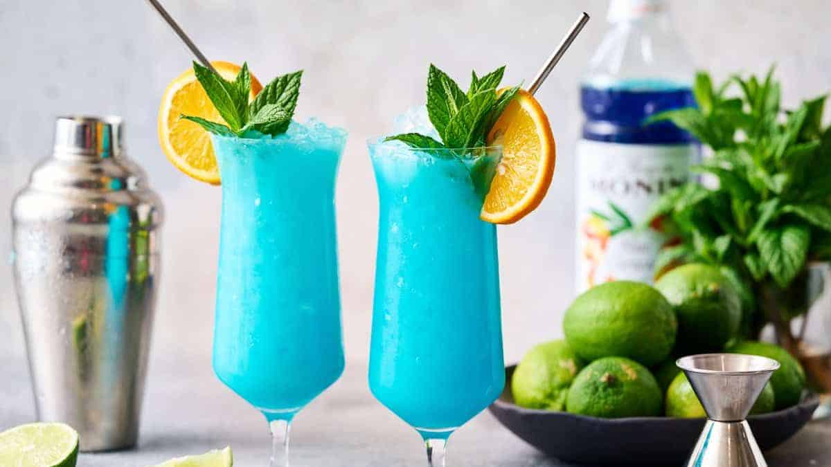 Two tall glass of mocktail drink designed with mint leaves and slices of oranges.