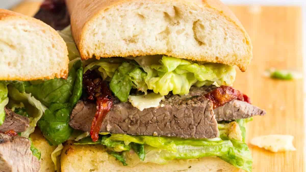 Close-up shot of Caesar Salad Steak Sandwich sliced in half. 