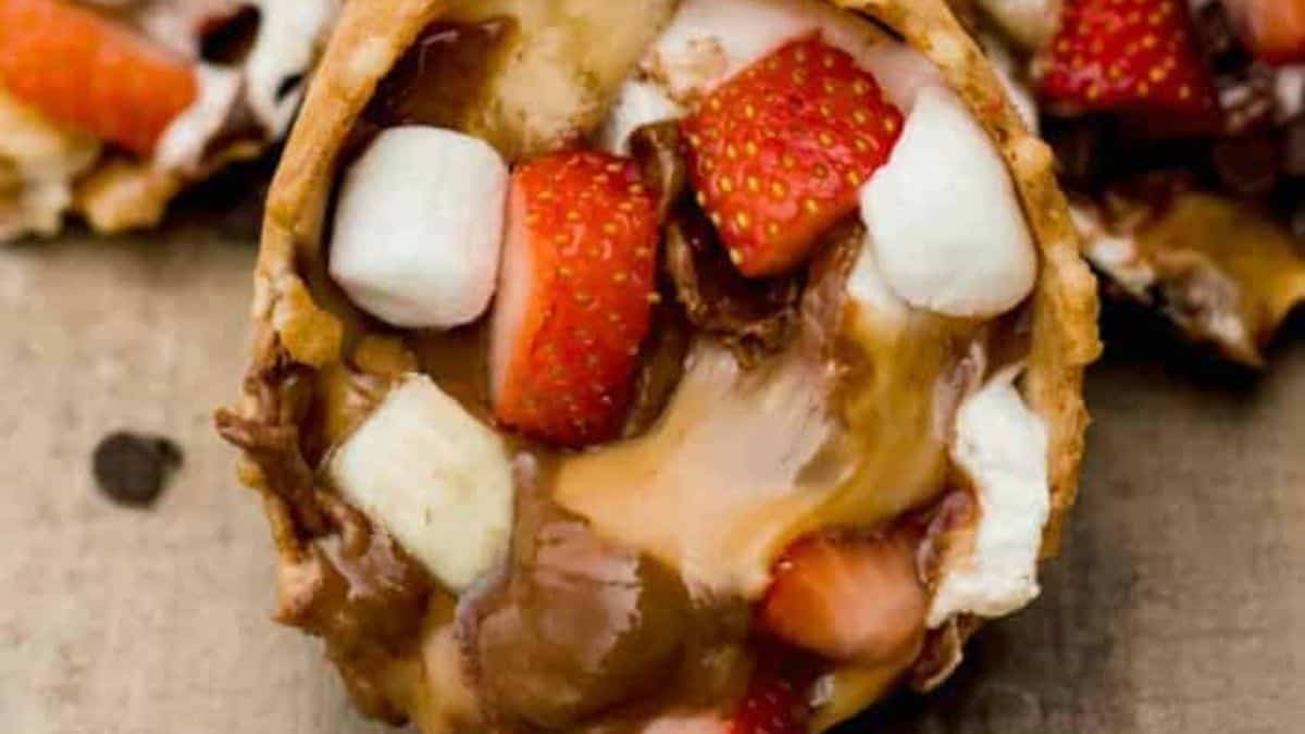 A close-up shot of campfire cone filled with slices of strawberries, melted chocolate, melted marshmallows,
