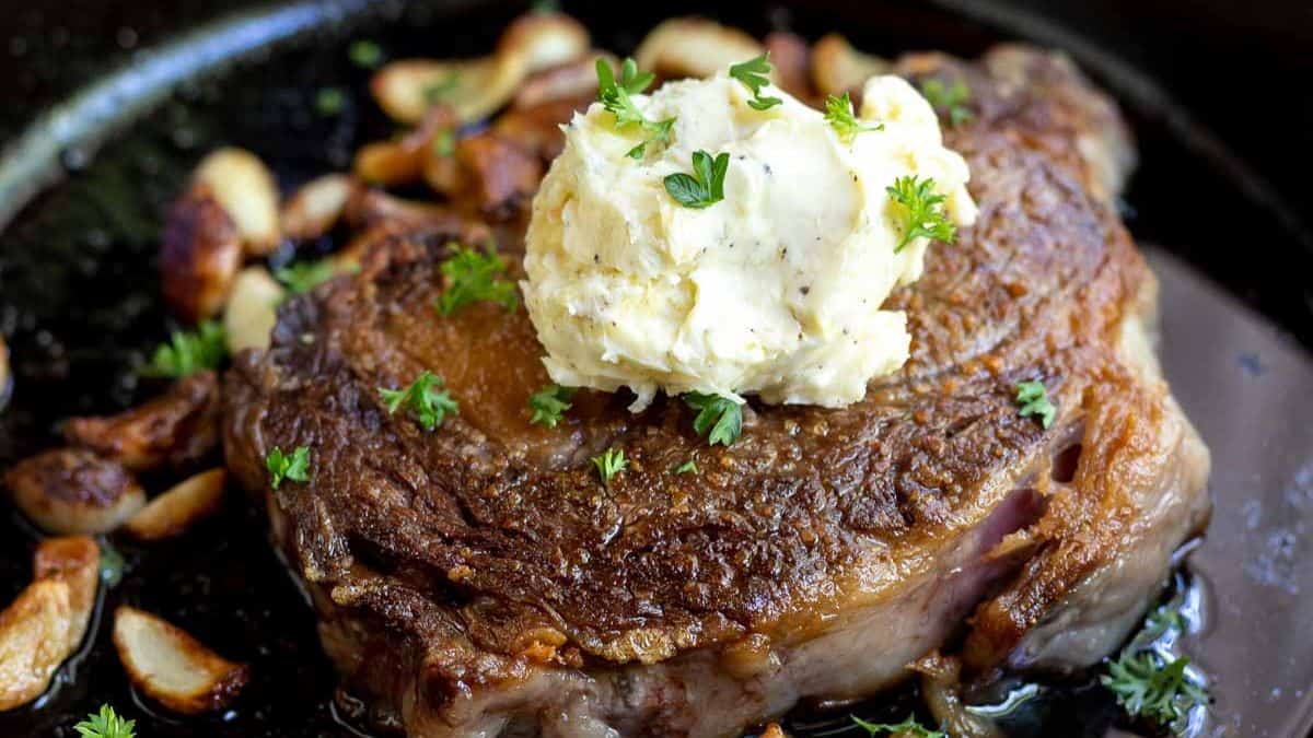 Ribeye steak with a dollop of garlic butter on top, cooked in cast iron.