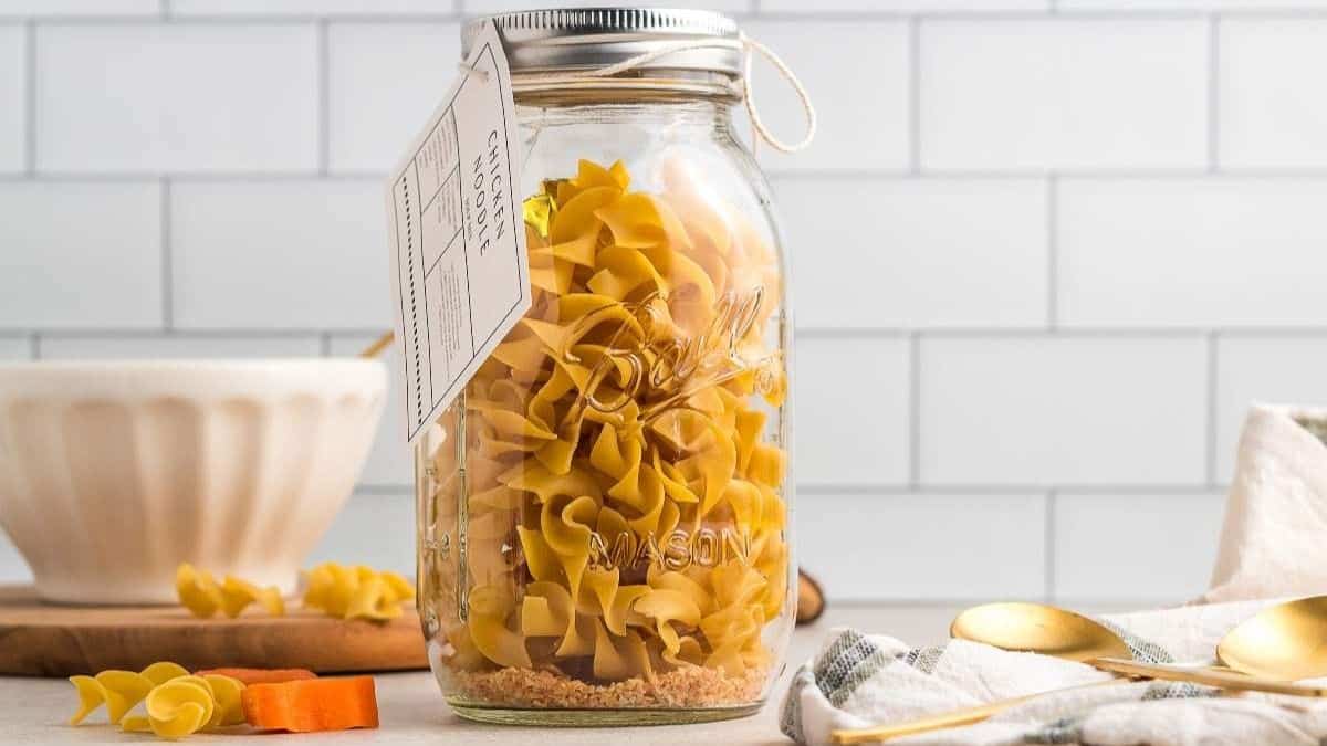Glass jar filled with dry ingredients for chicken noodle soup mix.