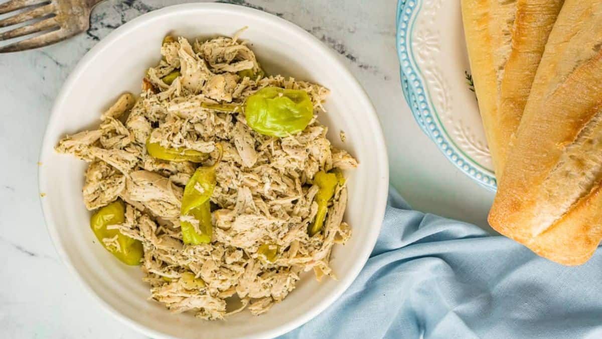 Top shot of A plate of Mississippi Chicken on the side two pieces of bread set on a plate. 