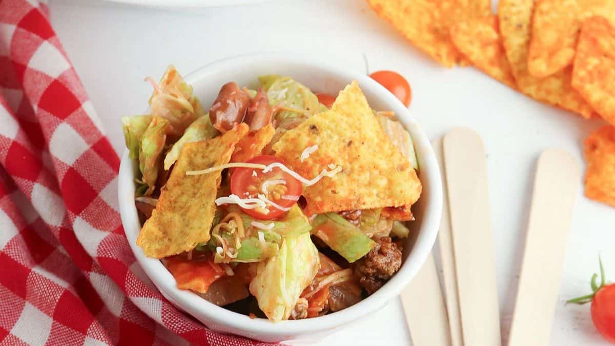 A small bowl filled with taco salad with Doritos. 