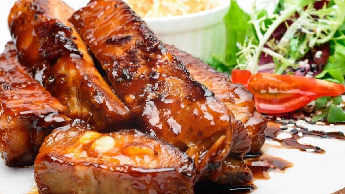 A close-up shot of a country style pork ribs set on a plate with some side salad. 