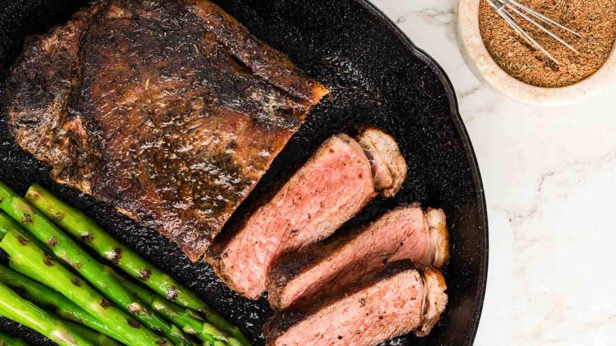 Sliced steak with asparagus set on a cast iron. 