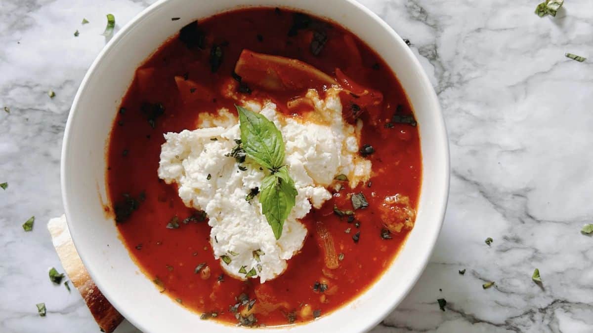 A bowl of Lasagna soup topped with cheese. 