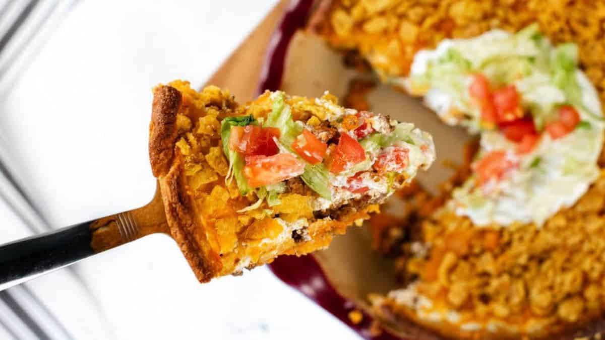 Corn chips layered with seasoned ground beef, cheese and taco toppings in a casserole dish.