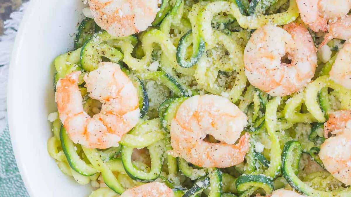 Garlic parmesan zoodles with sautéed shrimp and grated cheese.