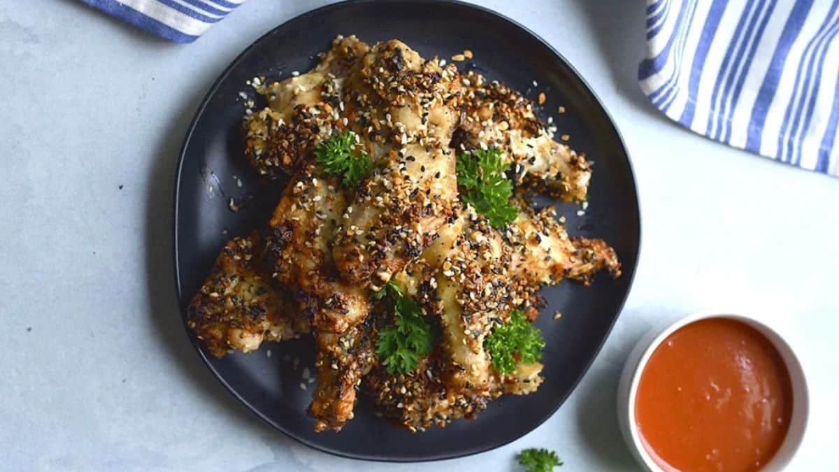 Top shot of a plate with chicken wings, and a dip on the side. 