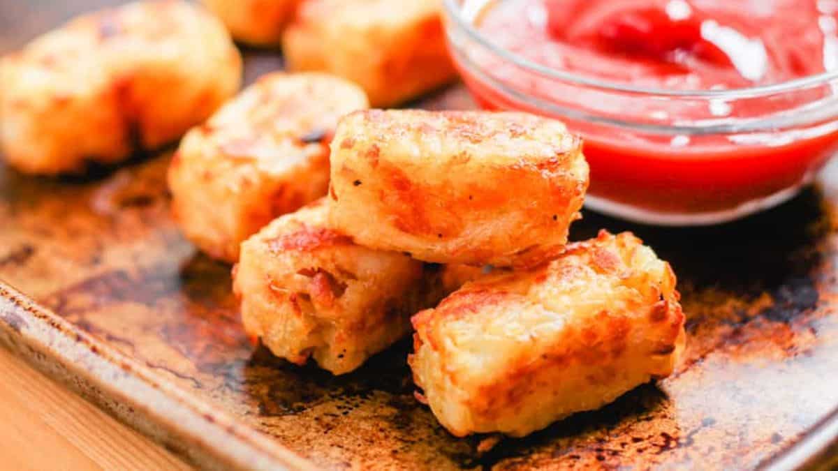Tater Tots served on a tray with a dipping sauce on the side.
