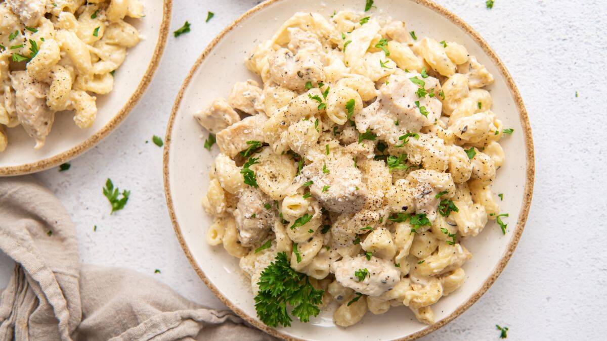 Two plates of Creamy Chicken Pasta with sprinkled parsley leaves. 