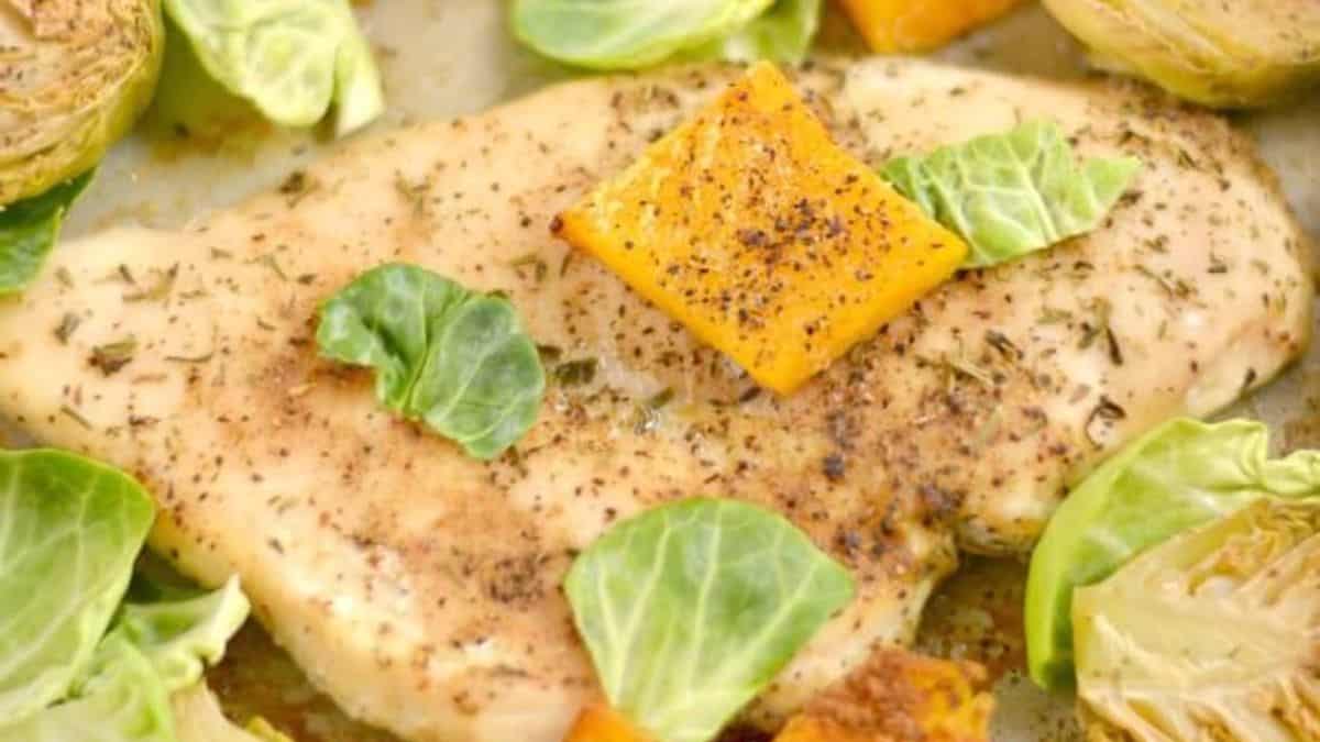 A close-up shot of a baked pan chicken with brussels sprouts and butternut squash.