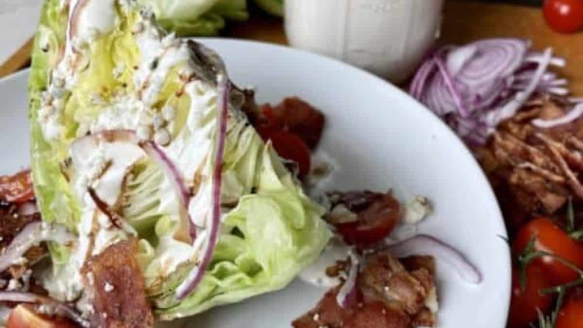 A plate with wedge salad and some dressing.