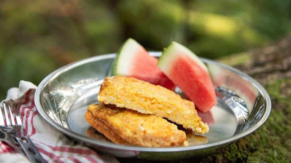 Pie Iron Breakfast Bake served in a plate with two wedge of watermelon. 
